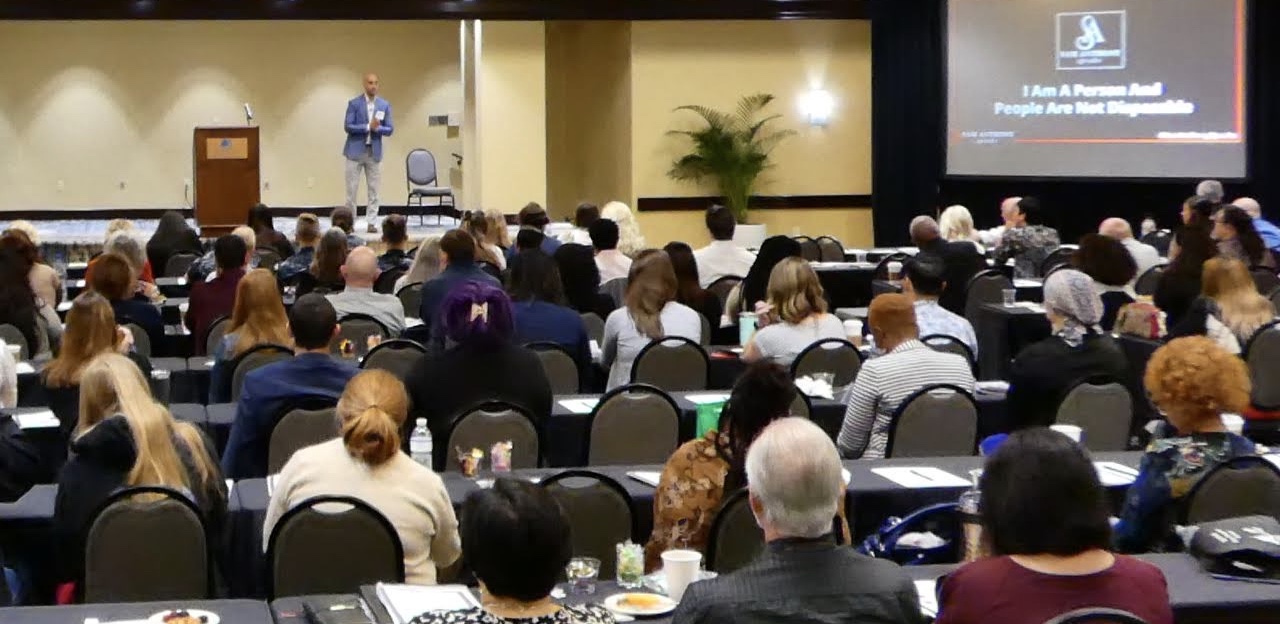 Sam Anthony speaking on stage to a room of professionals